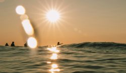 Surfer under setting sun